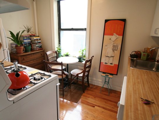 Love this intimate kitchen with small plants and pops of orange in the art and kettle. Via apartment therapy
